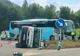 Furgoneta volcada y autobús detenido con el que colisionó en la rotonda de Aboño