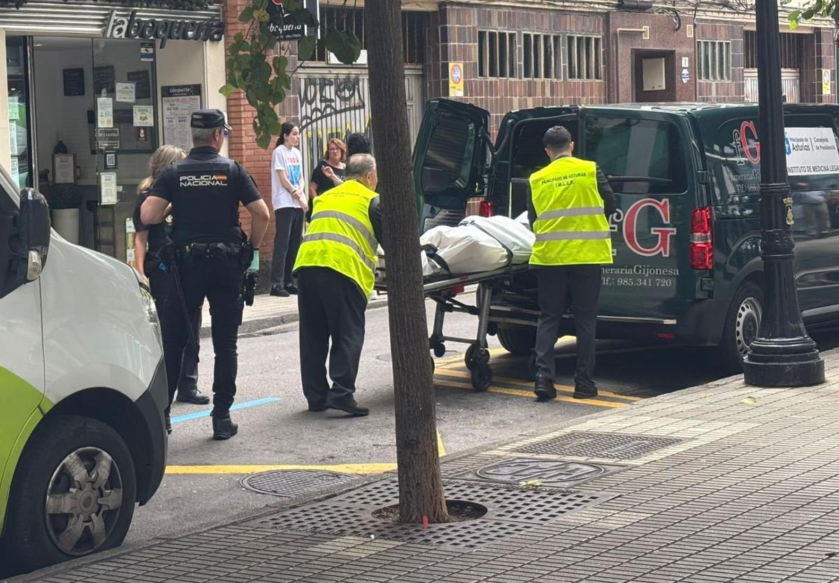 Trabajadores de la funeraria trasladan el cadáver hallado dentro del aseo del bar.