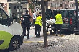 Trabajadores de la funeraria trasladan el cadáver hallado dentro del aseo del bar.