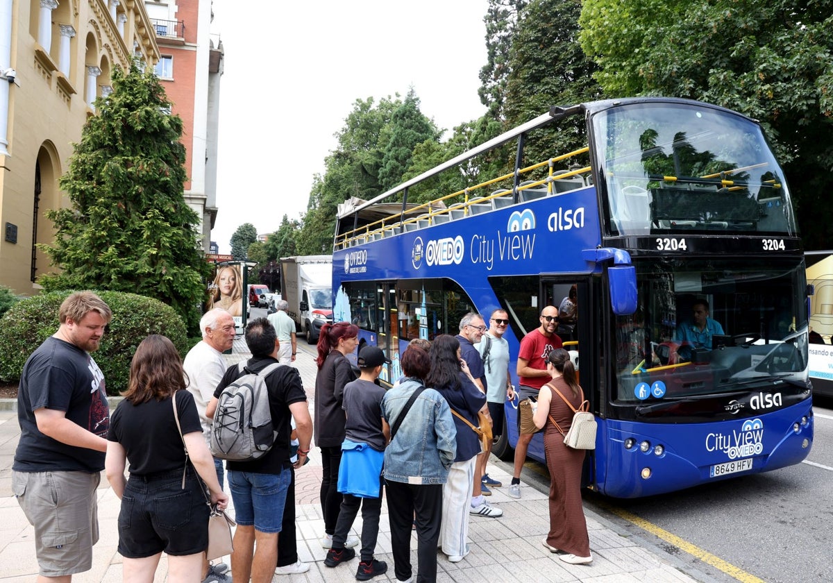 Usuarios haciendo cola para subir al bus turístico.