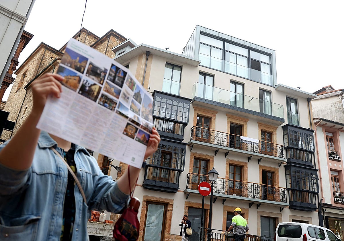 Una turista consulta un mapa de la ciudad ante el edificio de apartamentos turísticos Zalle Oviedo Suites.