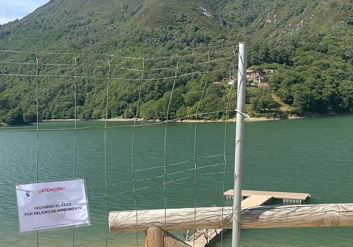 El acceso a los pantalanes del embalse navegable de Tanes, vallado y con la advertencia de peligro de hundimiento