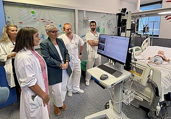 La doctora Consuelo Valles le muestra a la consejera de Salud el sistema de monitorización vídeo-encefalográfica mediante una simulación con un muñeco. Con ellas, la directora del HUCA, Beatriz López, y el enfermero José Aurelio Bartolomé y el médico residente Pedro García.