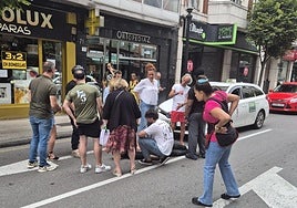 Un grupo de ciudadanos auxilia al conductor del patinete, que quedó tendido en la calzada de la avenida de la Costa.