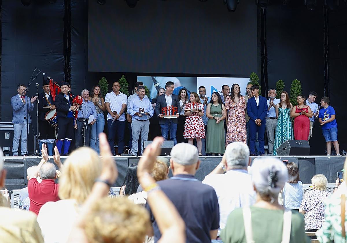Foto de familia de Miguel Ánxel Montenegro, Xuaco Areces, Fonso 'Les Regueres', César González, Manuel López, Andrea Méndez (hija de María Luisa Martínez), Fernando Entralgo, Esteban Verdeja, Valentín García, Lorena Corripio, Sergio Menéndez, Sandra Miranda, Alicia Villanueva, Miguel Rojo, Claudia Abad, Valentín Fuente, Cristina Sánchez, Óliver Suárez, Néstor Díaz, José Ramón Fiaño, Lucía Fernández, Bárbara Riesco, Jairo Pérez y Mario González, tras la entrega de premios, en el escenario de la plaza Mayor.