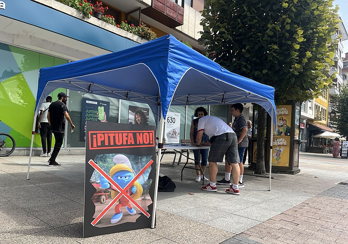 Al fondo, vecinos firmando en el puesto del PP, presidido por un cartel contra la figura de la pitufa, junto a la plaza cubierta.