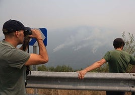 Una persona observa con sus binoculares el incendio en Genestoso.