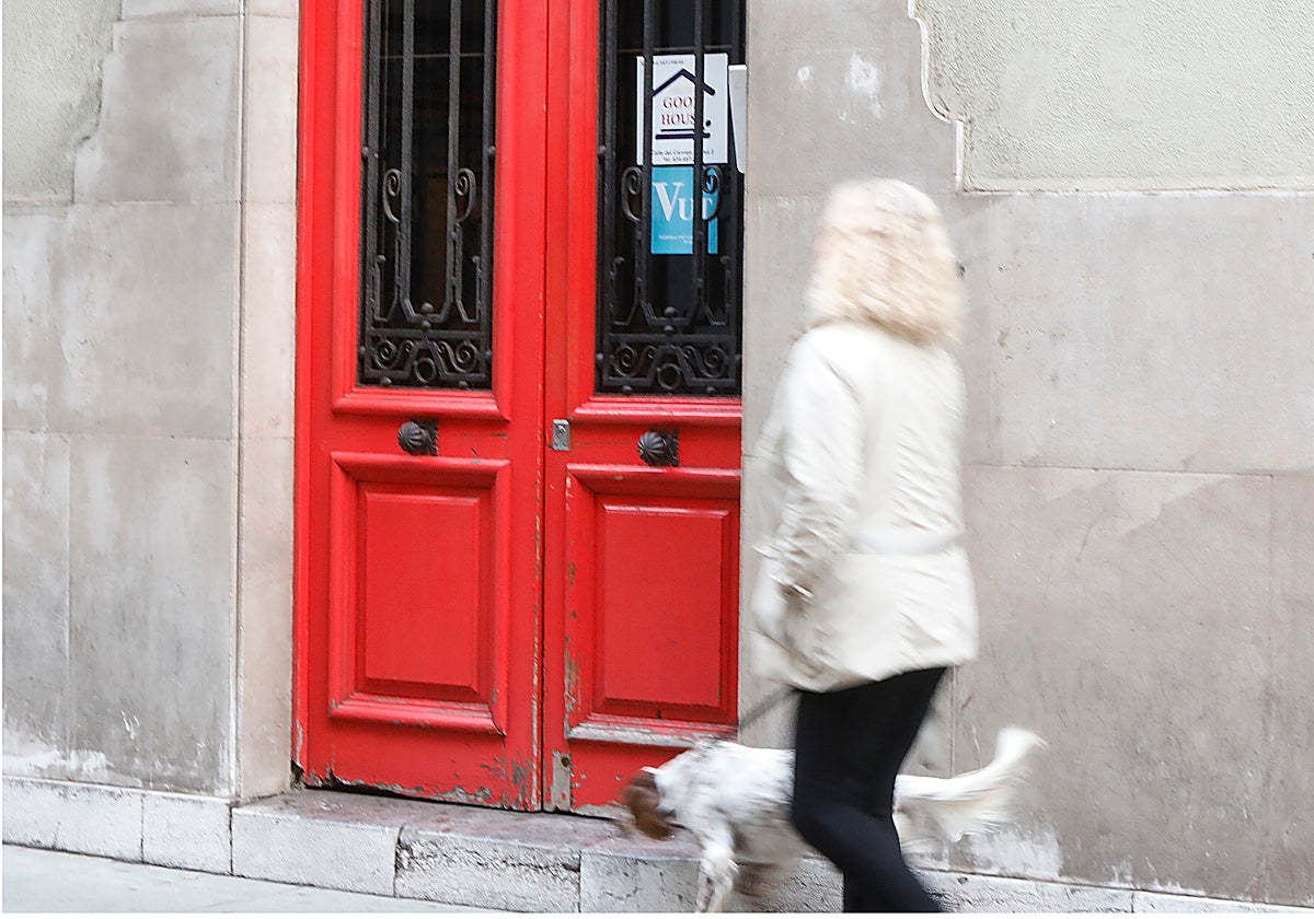 Una mujer pasea con su perro ante una Vivienda de Uso Turístico de Gijón.