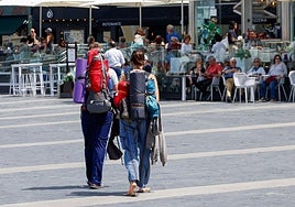 Una pareja de turistas camina por los Jardines de la Reina de Gijón.