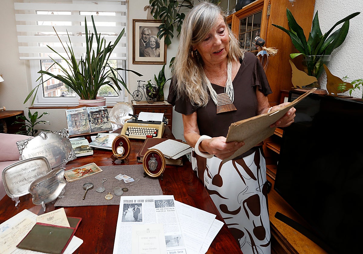 Flor Hevia muestra objetos históricos de Víctor Labrada con el cronista gijonés y su esposa Florinda Hevia en una foto enmarcada en la pared del fondo.