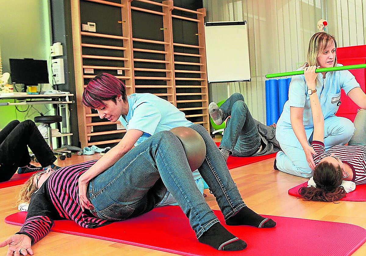 Dos fisioterapeutas practican ejercicios de espalda con pacientes.