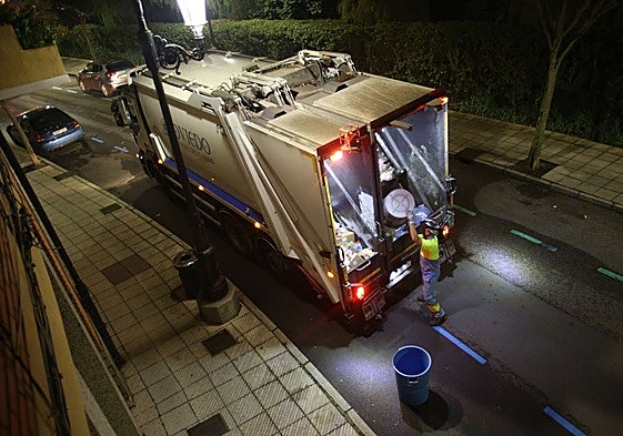 Un operario vuelca un cubo de la basura en el camión de recogida en la calle de Leopoldo Alas.