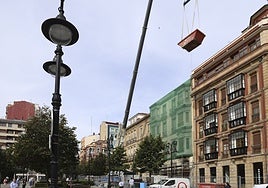Una grúa eleva un contenedor de obra para los trabajos de reforma del teatro Jovellanos, de Gijón.