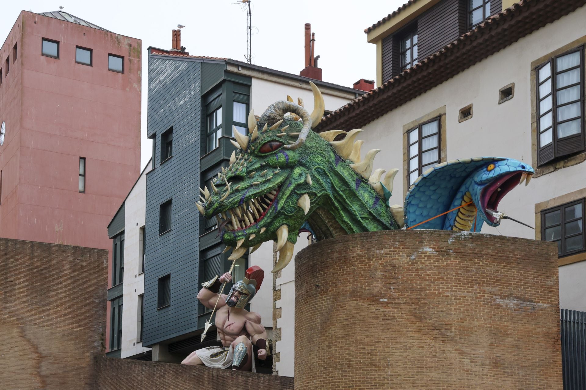 La figura de un romano, la cabeza de un dragón y la de una serpiente decoran los restos de la antigua muralla en Cimavilla.