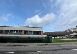 Inmueble de la antigua comisaría de Policía de La Pola, con el paraguas de Ildefonso Sánchez del Río al fondo.