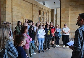 Un público de todas las edades escucha las explicaciones de uno de los guías bajo los soportales del edificio construido por Luis Moya.