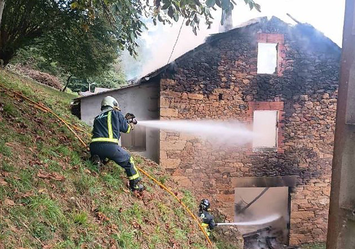 Los bomberos sofocan las llamas que arrasaron parte de la vivienda.
