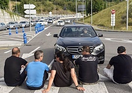 Varios taxistas cortan el paso a un vehículo VTC junto al aeropuerto de Bilbao durante una huelga.