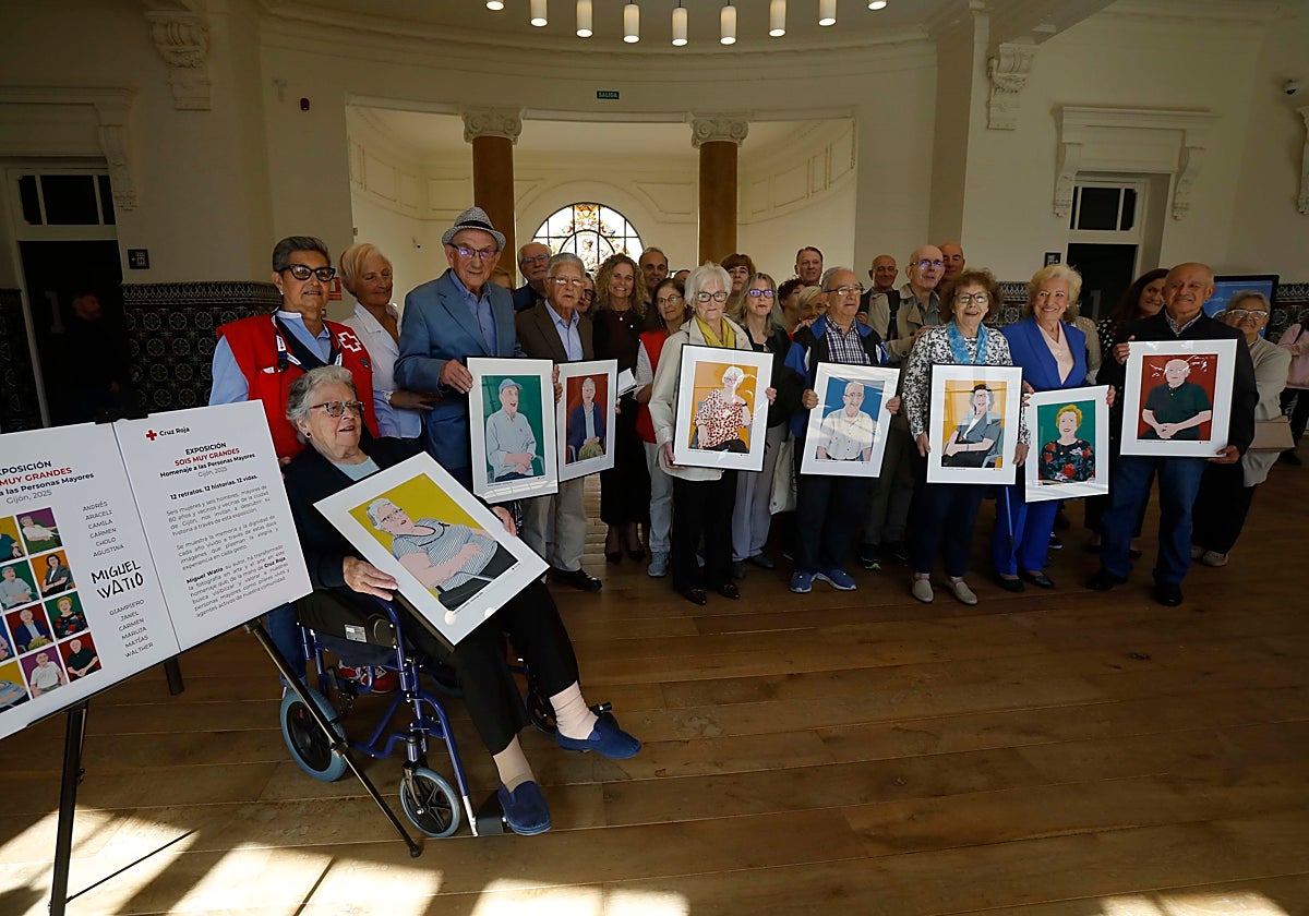 Protagonistas de la muestra 'Sois muy grandes,' junto a organizadores y voluntarios de Cruz Roja, portan los cuadros con sus retratos tras la jornada en la Escuela de Comercio.