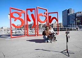 Una pareja se fotografía ante las Letronas de Gijón.