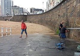 Dos operarios, en plena labor para colocar el nuevo tramo de barandilla en la Rampla de la playa de San Lorenzo, de Gijón.