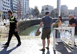 De espaldas, el joven que rescató a la mujer en Gijón.