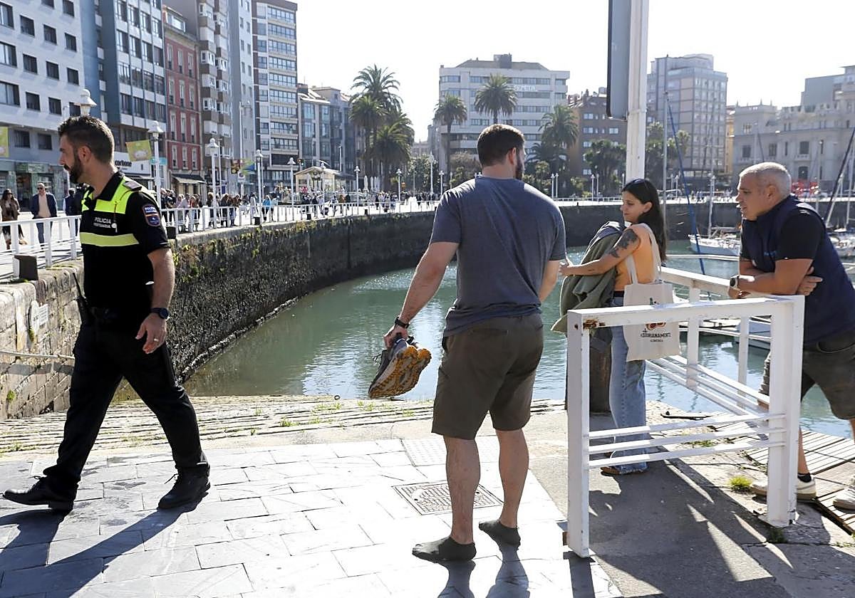 De espaldas, el joven que rescató a la mujer en Gijón.