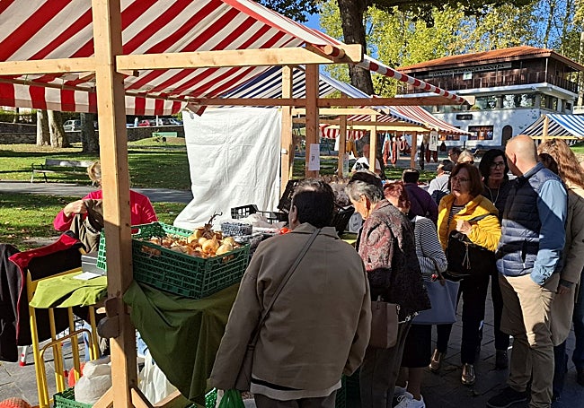 Clientes interesados en los puestos de verduras frescas del centro del parque.