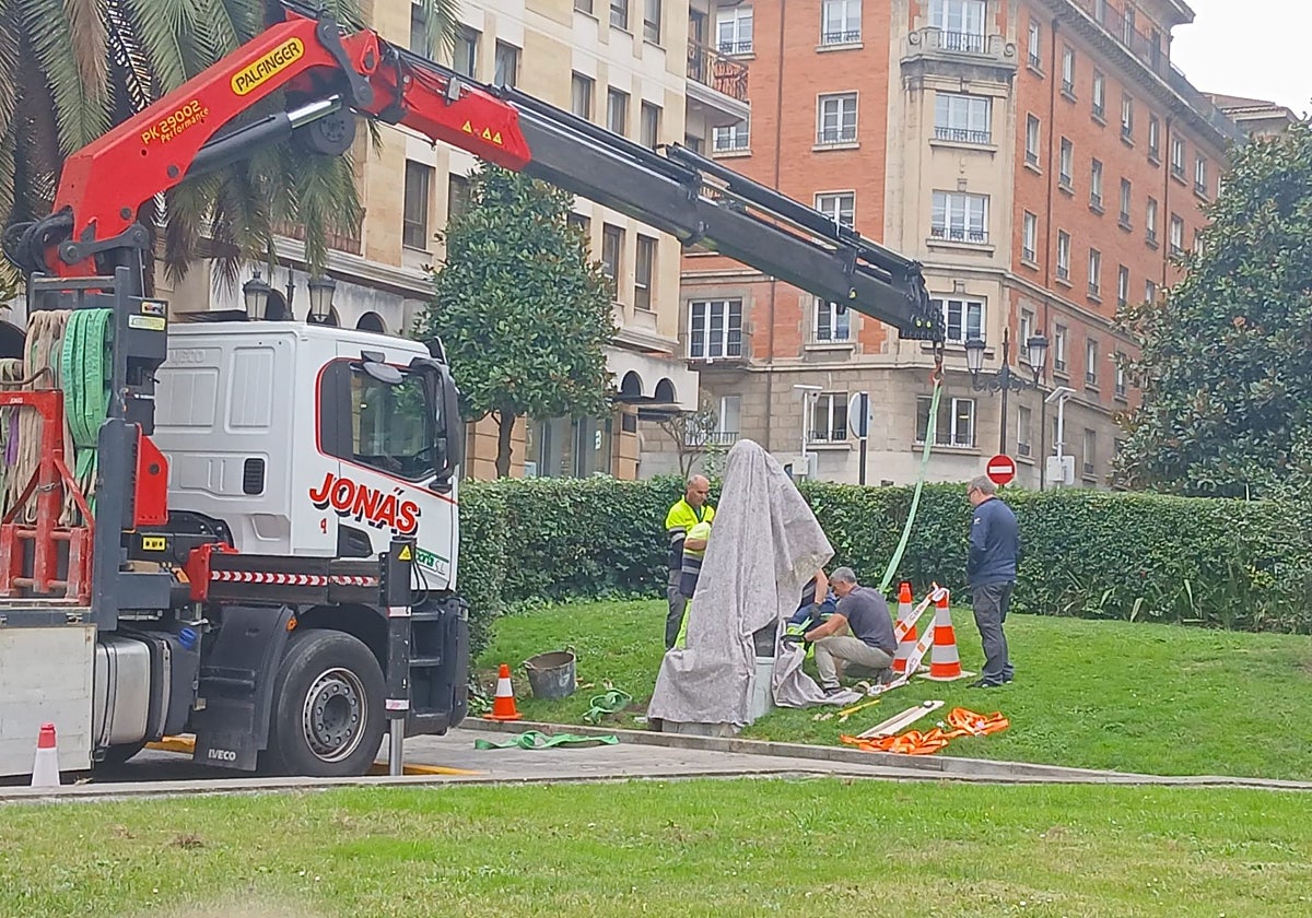 Los operarios colocando la escultura.