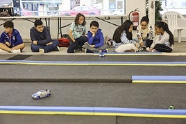 Varios participantes siguen una carrera teledirigida mientras otros resuelven en grupo una de las actividades formativas.