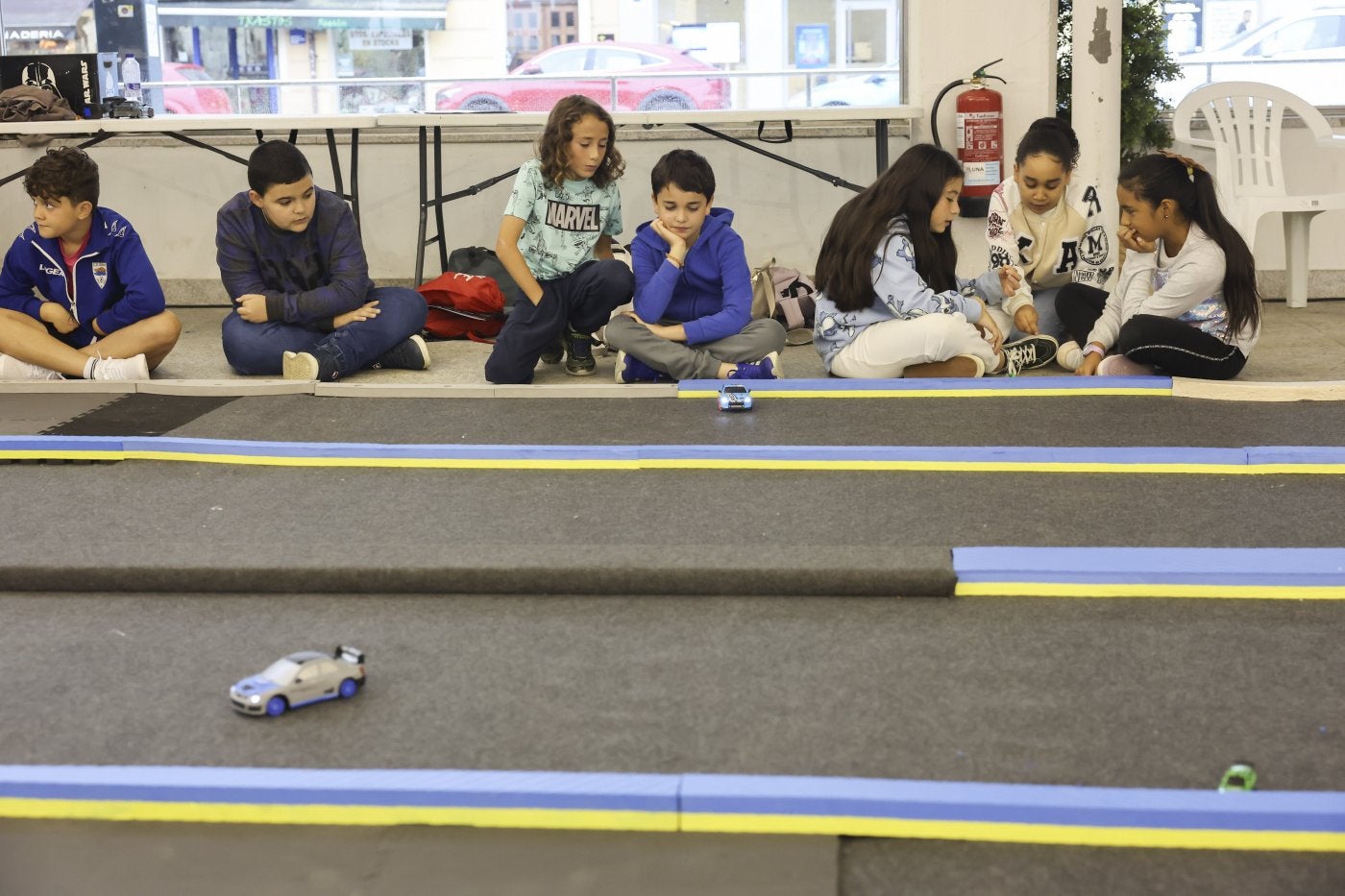 Varios participantes siguen una carrera teledirigida mientras otros resuelven en grupo una de las actividades formativas.