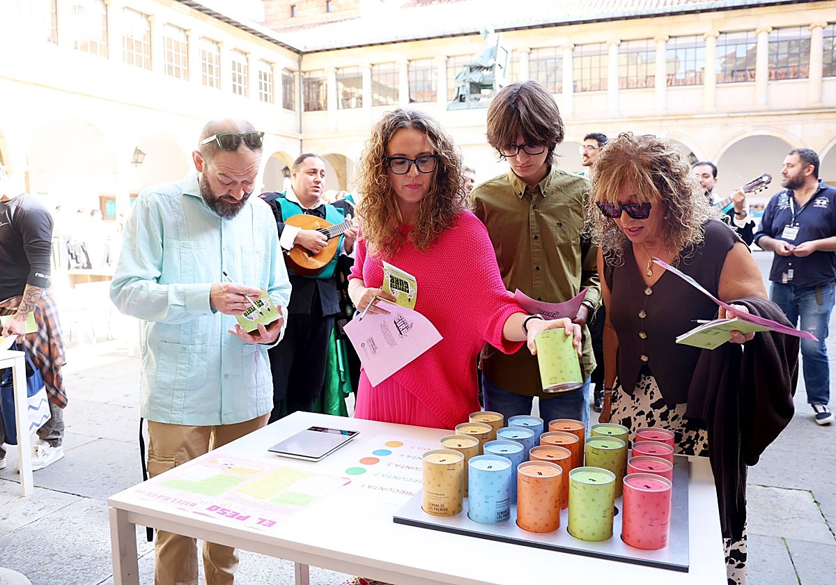 Un grupo de participantes en la yincana durante el juego 'El peso de la inteligencia pura', mientras la Tuna les canta algunas pistas, en el edificio histórico de la Universidad.