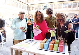 Un grupo de participantes en la yincana durante el juego 'El peso de la inteligencia pura', mientras la Tuna les canta algunas pistas, en el edificio histórico de la Universidad.