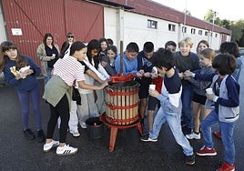 Los niños prensando la magaya en la jornada educativa dentro del Día Internacional de la Manzana.