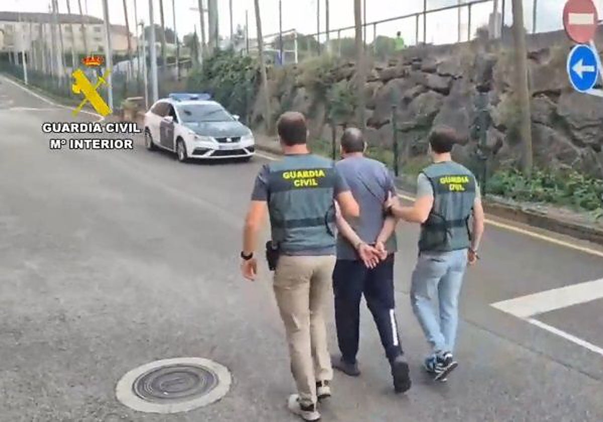 El detenido, custodiado por dos guardia civiles en el acuartelamiento de Gijón.