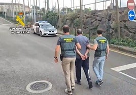 El detenido, custodiado por dos guardia civiles en el acuartelamiento de Gijón.