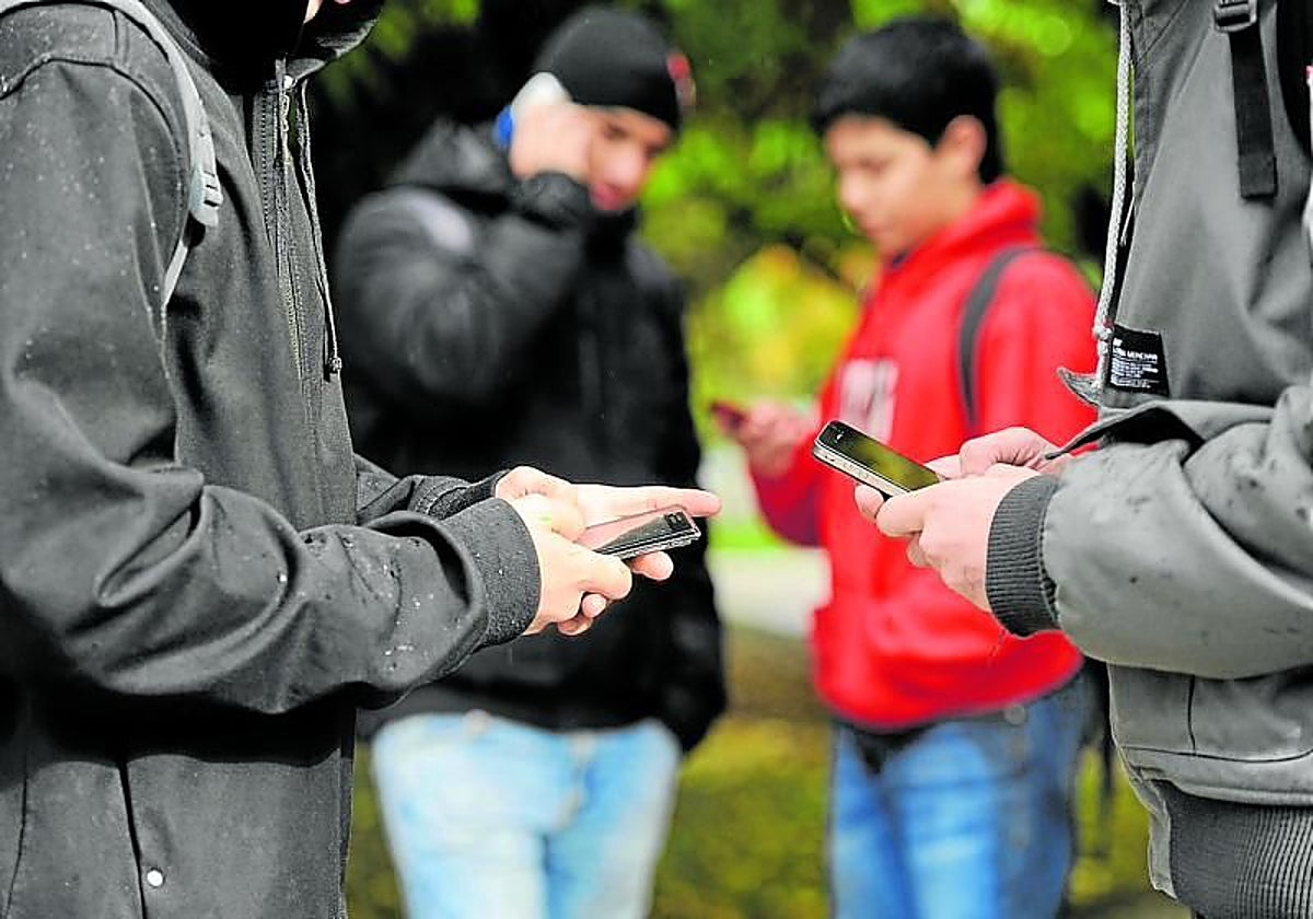 Un grupo de jóvenes inmersos en sus dispositivos móviles, sin interactuar entre ellos.
