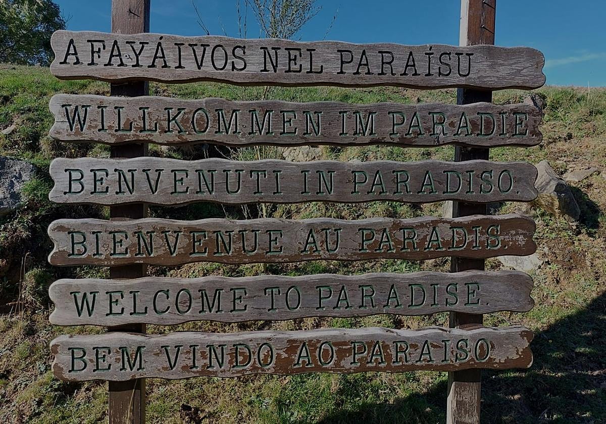 Cartel con «Bienvenidos al Paraíso» en varios idiomas en la vega de Brañagallones.