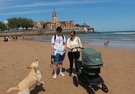 Una familia, con un bebé y un perro, en la playa de San Lorenzo de Gijón.