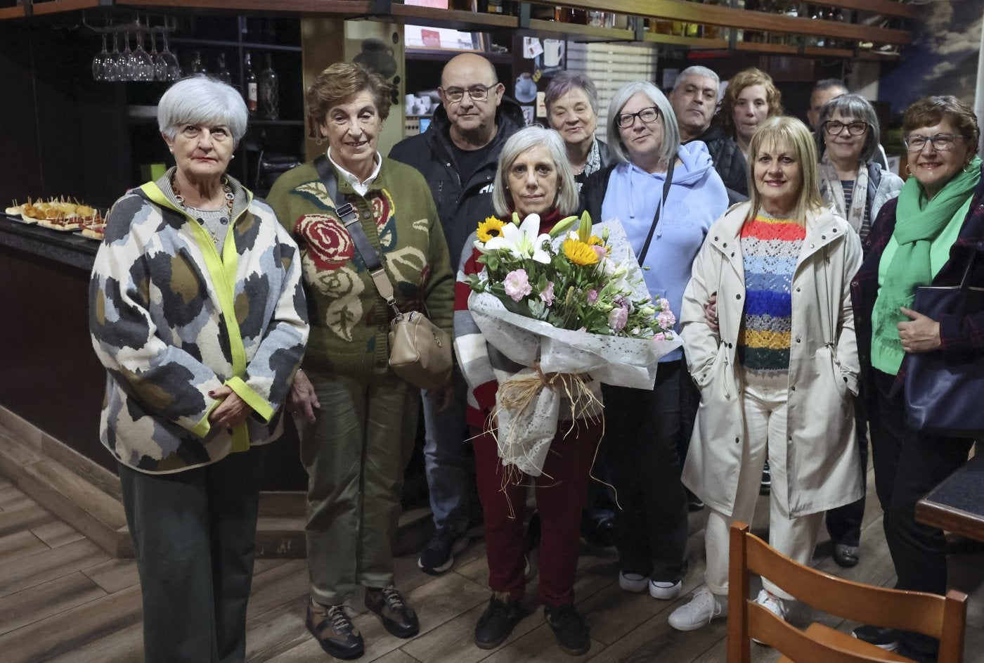 Sole, con el ramo de flores, y su marido Rogelio detrás y algunos clientes en el inicio de la tarde noche de barra libre.