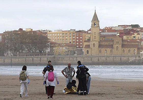 Agentes de la Policía Local y sanitarios atienden a la joven indispuesta en la playa de San Lorenzo.