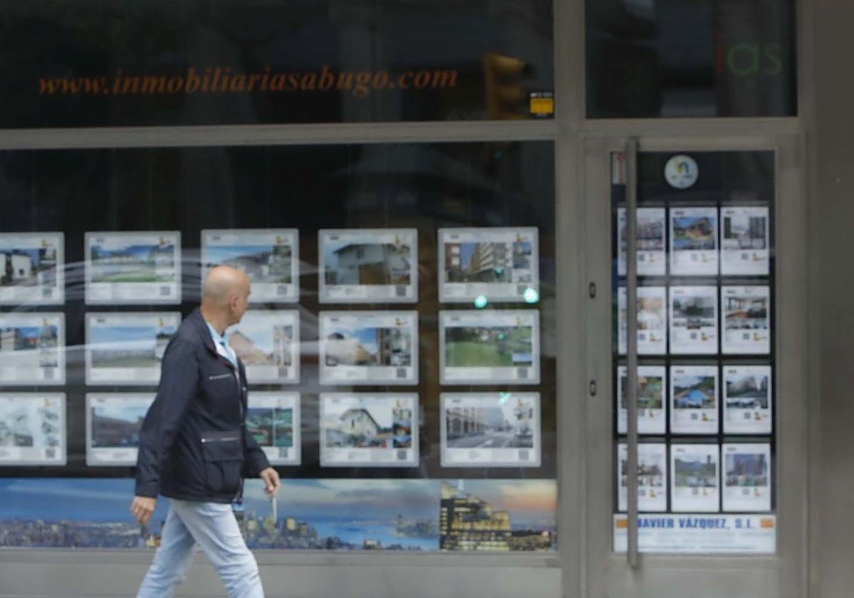 Un ciudadano se fija en las ofertas de una inmobiliaria de Gijón.