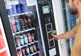 Un joven adquiere bebidas energéticas en una máquina expendedora.
