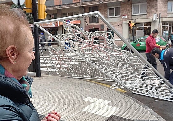 En primer plano, la mujer que sufrió el golpe del arco navideño desprendido en Pérez de Ayala esta mañana. A la derecha, policías locales proceden a su retirada.