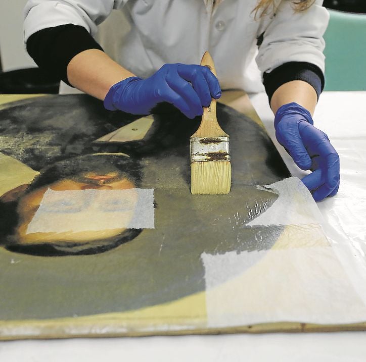 Laura Rodríguez Noval procede a empapelar con papel japonés uno de los retratos para proteger la policromía. : fotos de paloma ucha