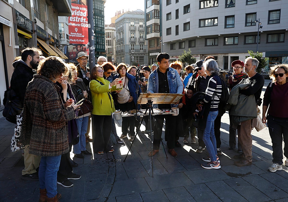 Un grupo de turistas observa cómo un artista pinta un cuadro en el entorno de la plaza del Marqués.