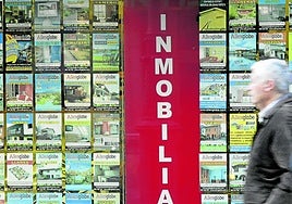 Dos hombres caminan frente al escaparate de una inmobiliaria.