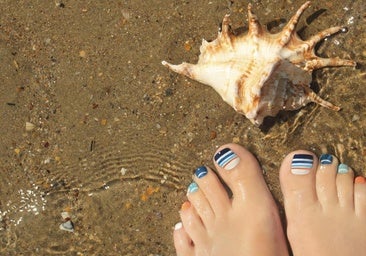 Unos pies con las uñas pintada con esmalte de colores.