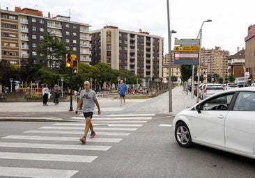 Un vehículos espera con su luz en ámbar, mientras los peatones cruzan en verde.