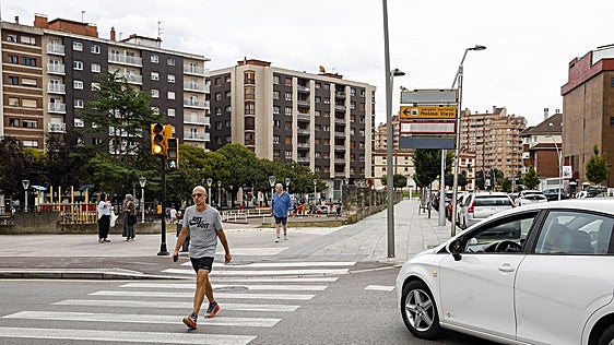 Un vehículos espera con su luz en ámbar, mientras los peatones cruzan en verde.